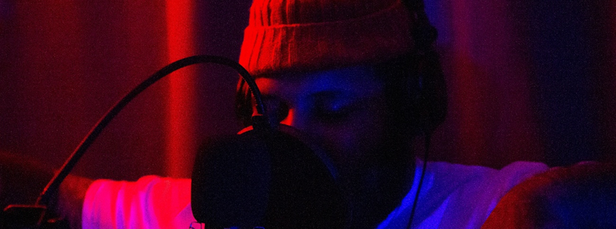 Un artista frente a un micrófono durante una sesión de grabación.