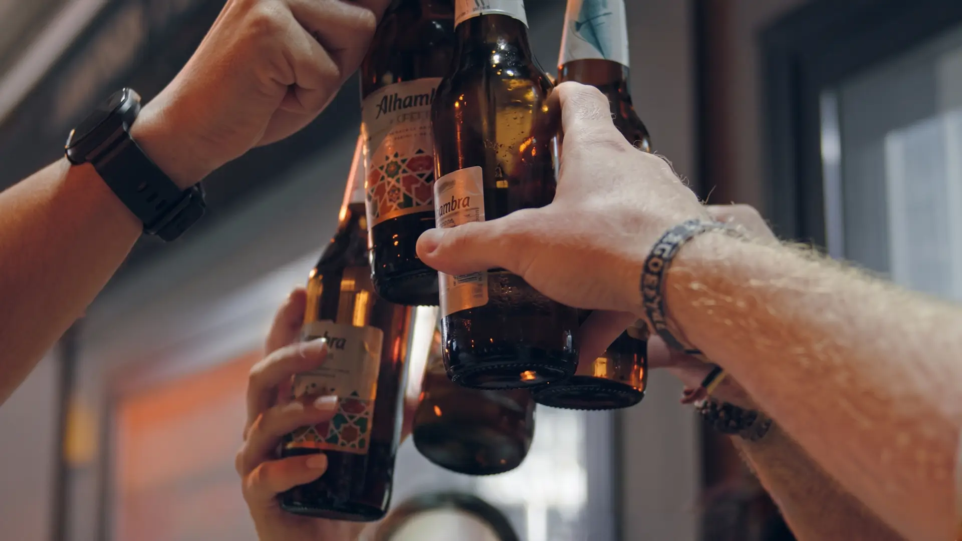 Varias personas brindan con botellas de Alhambra Especial