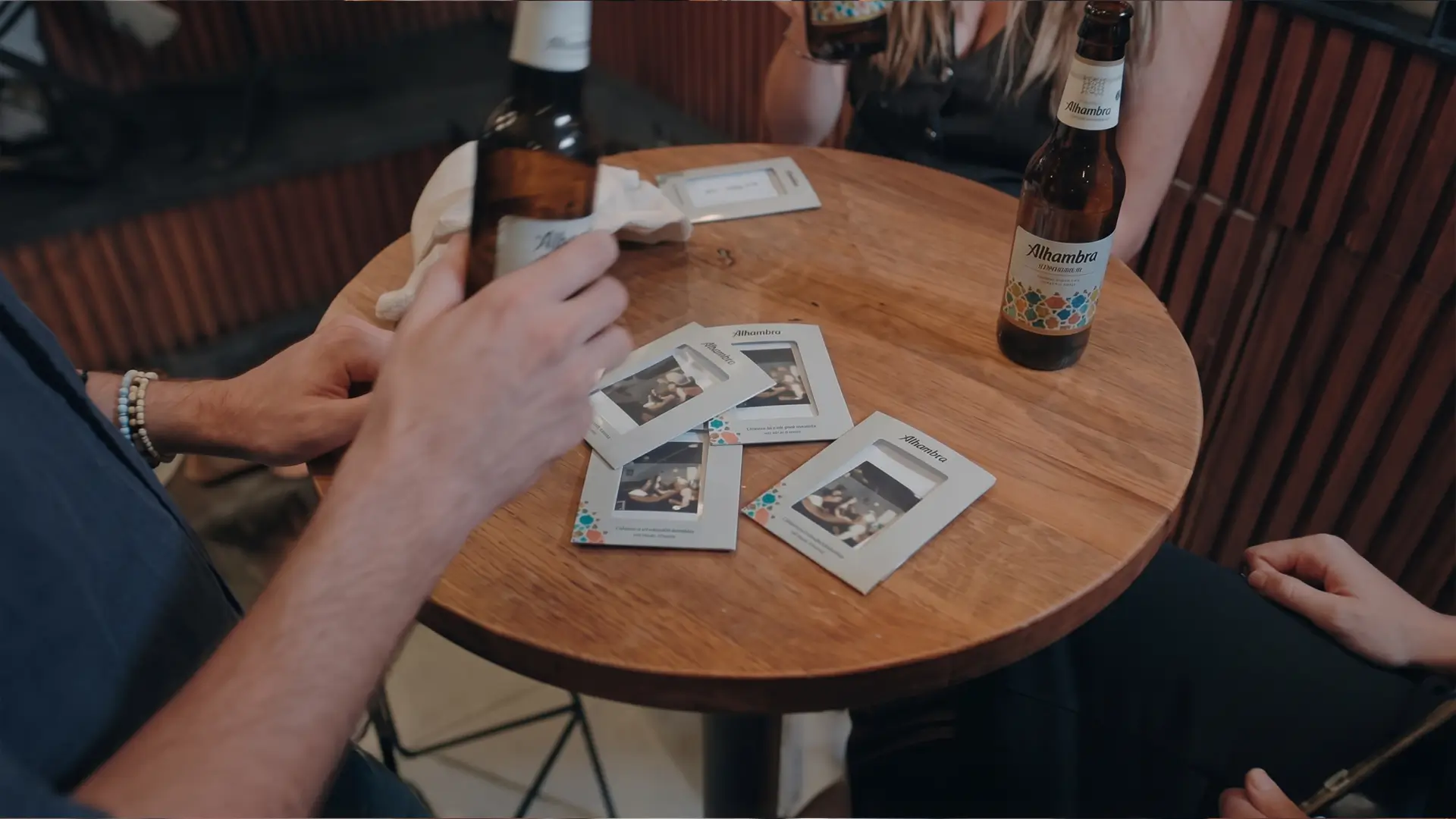 Fotografías Polaroid y una botella de Alhambra Especial sobre una mesa